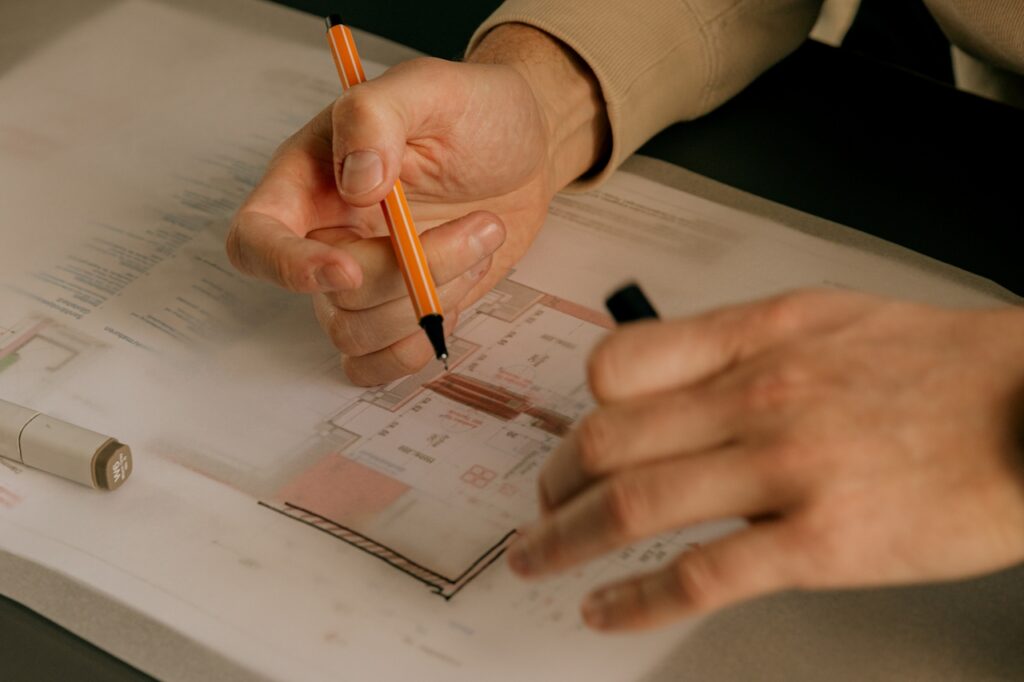 Drawing on top of detailed floor plans. Close up on hands.